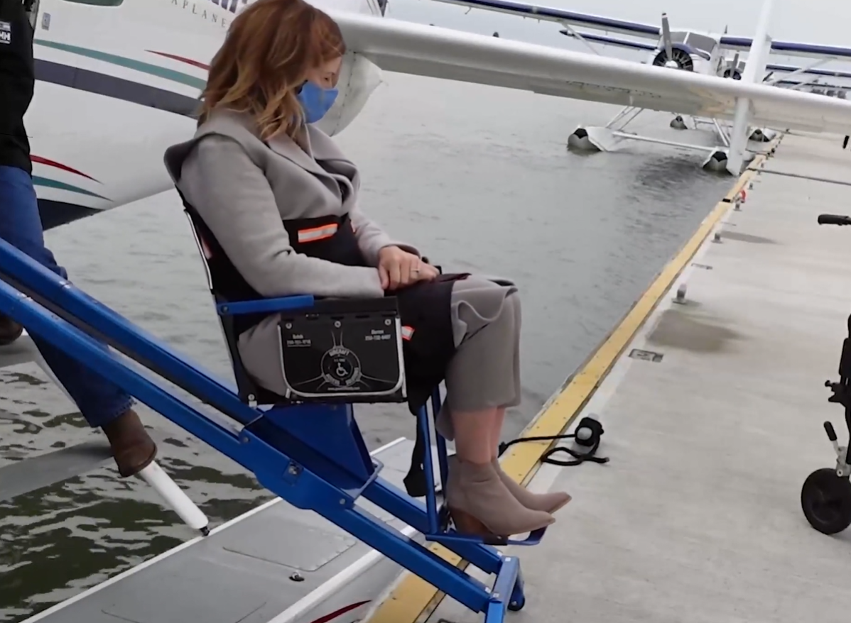 A floatplane passenger with mobility issues disembarks an aircraft with the help of a special lift