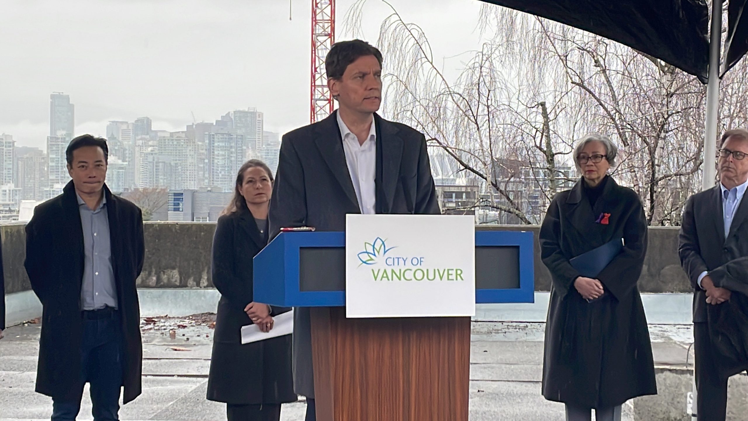B.C. Premier David Eby talking at a podium, behind him is Vancouver Mayor Ken Sim
