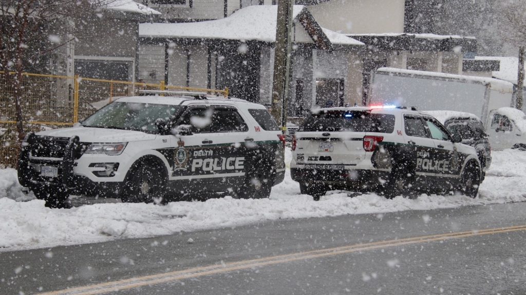 two delta police cruisers parked in the snow