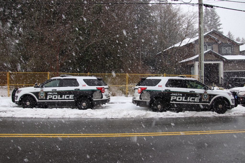 two delta police cruisers parked in the snow