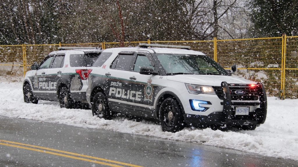 two delta police cruisers parked in the snow