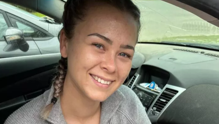 A woman is shown smiling and sitting in a car.