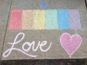 Locals in Langley helped cover up hateful graffiti with the word love, and a rainbow in chalk is depicted 