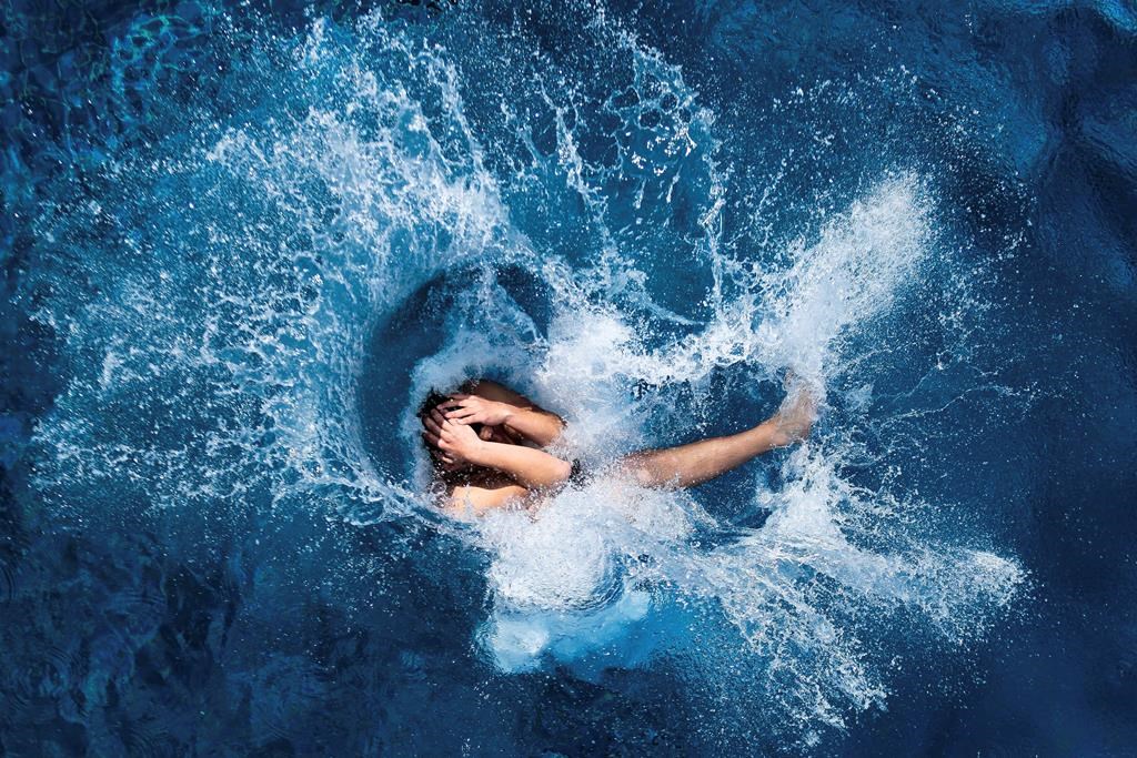 A boy jumps into the water at the Olympic open air public pool. (AP Photo/Markus Schreiber, File)