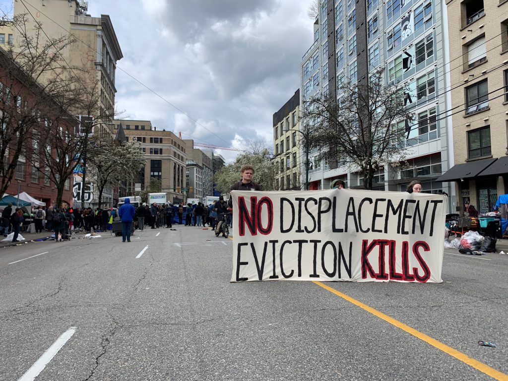 a large sign reads no displacement eviction kills. On Wednesady part of East Hastings street was shut down as part of the city's plan to decamp the area.