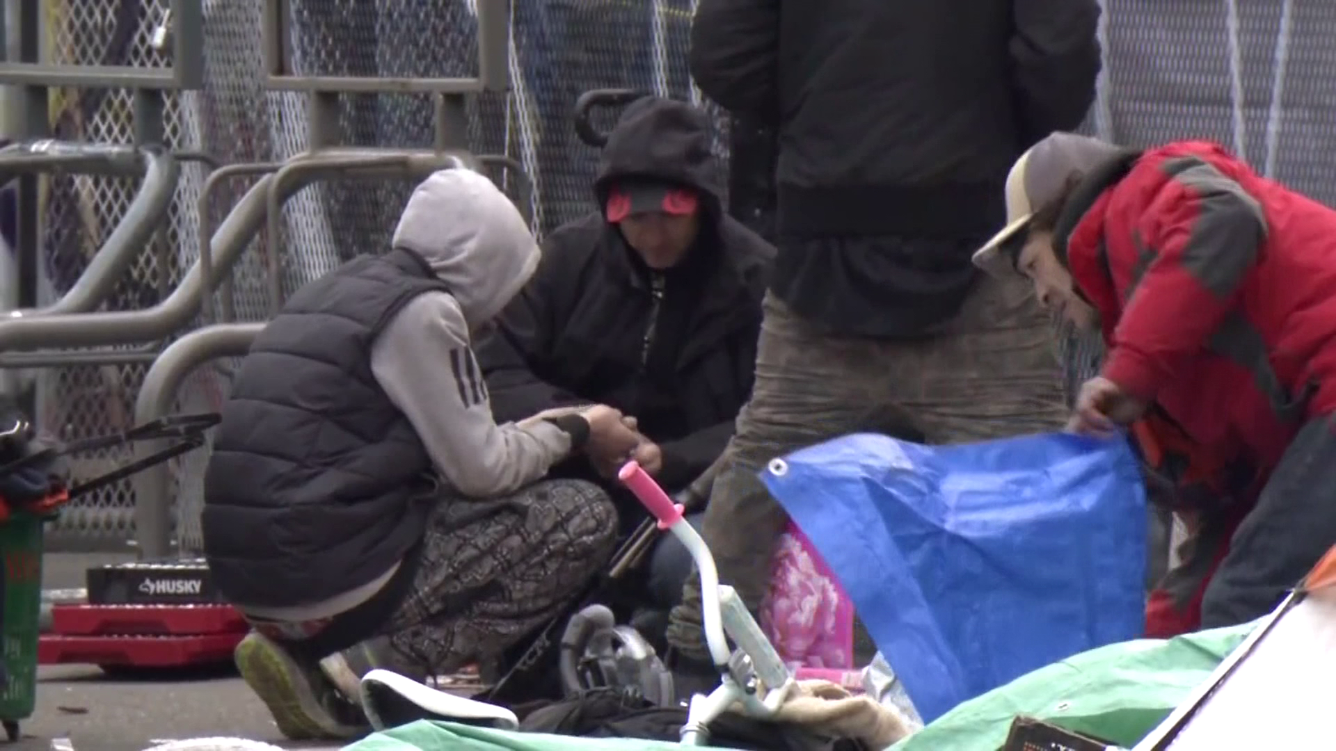 A group gathers on the sidewalk of East Hastings Street