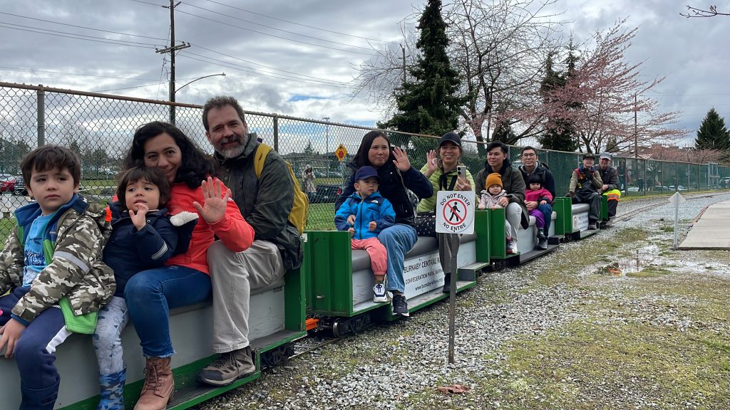 people of different ages on the cars of a miniature train