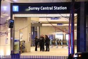 Police stand gathered inside at Surrey Central SkyTrain Station.