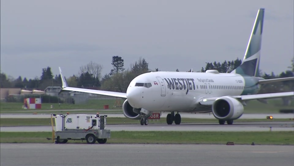 a white westjet airplane at the vancouver international airport