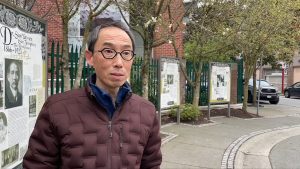 a man looking into camera wearing a red jacket and glasses outside in vancouver. Henry Tsang is an author and historian that focuses on the anti asain riots of 1907 in Vancouver.