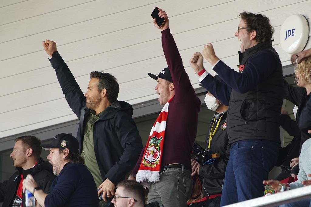 FILE - Wrexham owners, Ryan Reynolds, center left and Rob McElhenney, center, celebrate their side's first goal of the game, scored by Harry Lennon during the Vanarama National League match against Torquay United, at the Racecourse Ground, Wrexham, England, on Oct. 30, 2021. Soccer sensation Wrexham AFC is coming to America. The fifth-tier Welsh side, which has become a global fan favorite since Hollywood stars Reynolds and McElhenney bought it and then launched a documentary series, "Welcome to Wrexham," will play Manchester United in a friendly on July 25, 2023. (Peter Byrne/PA via AP, File)