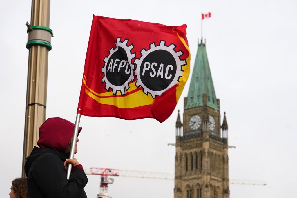 A PSAC worker holds a flag on a picket line in Ottawa, Wednesday, April 19, 2023