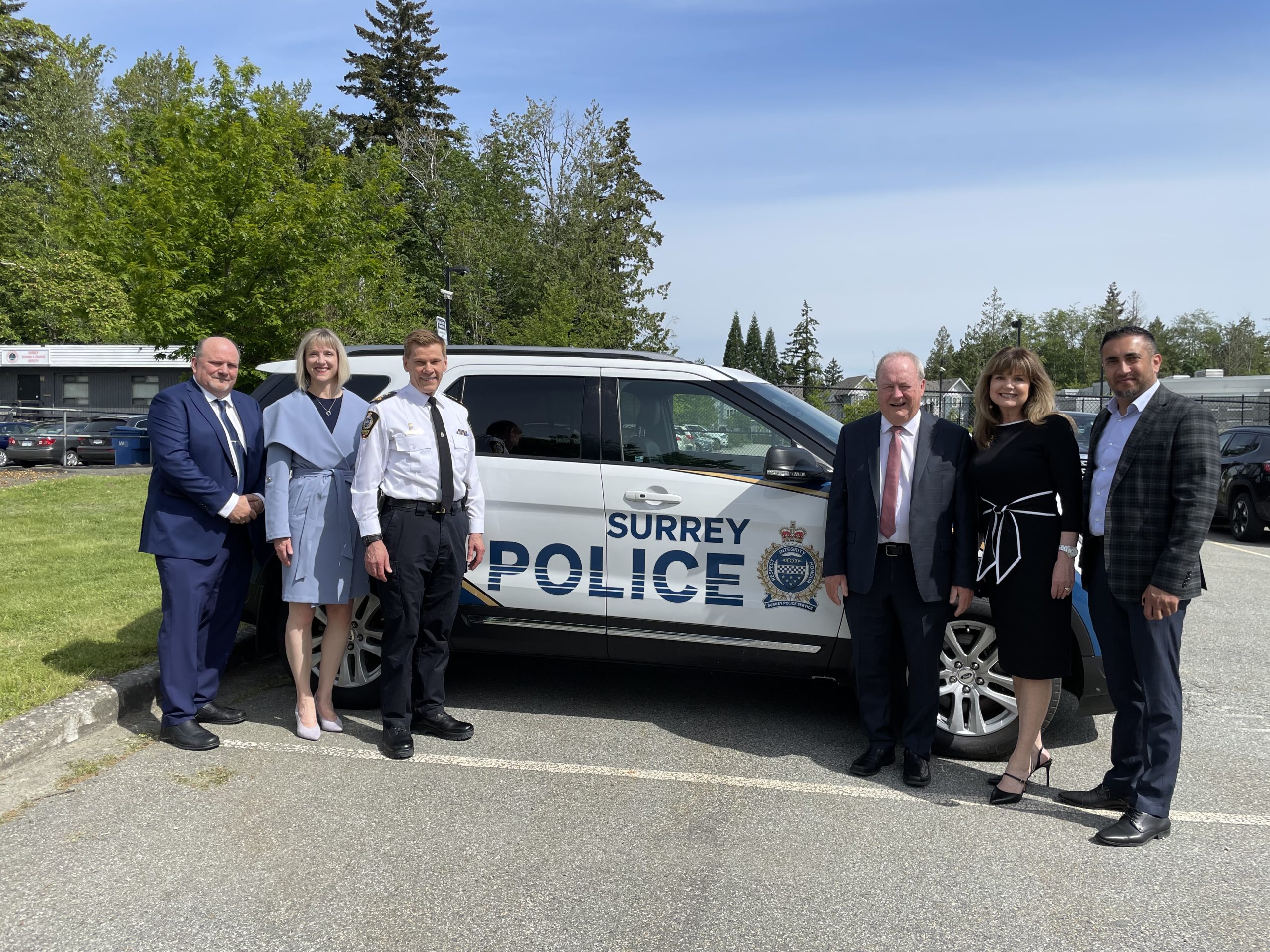 Doug McCallum (centre right) alongside other Safe Surrey Coalition members posing next to a Surrey Police Services vehicle. 