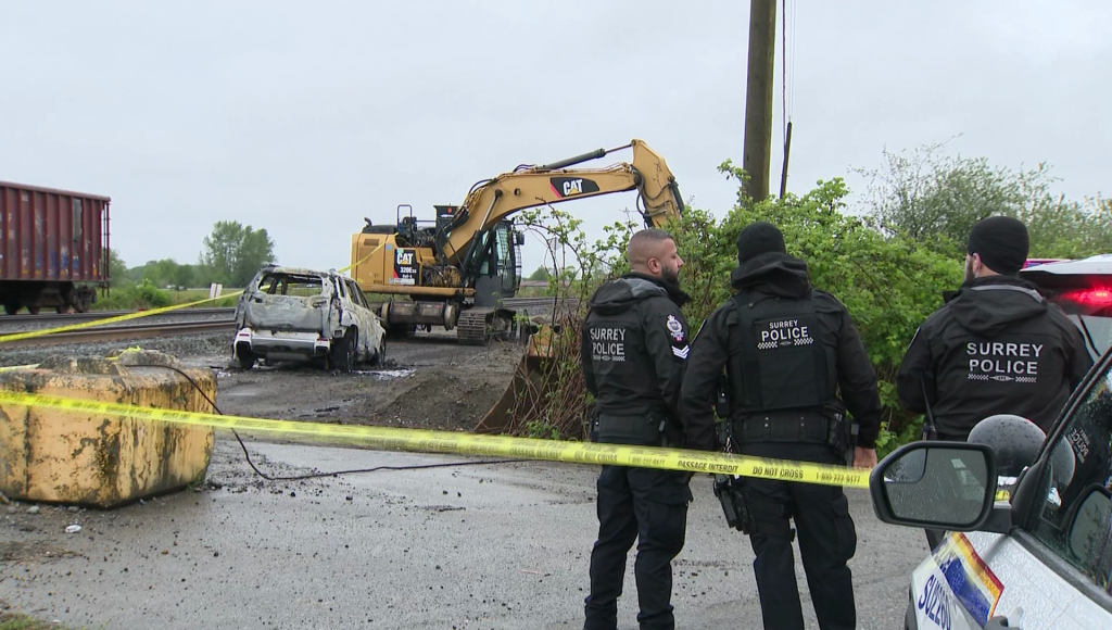 Police stand near a burnt out vehicle