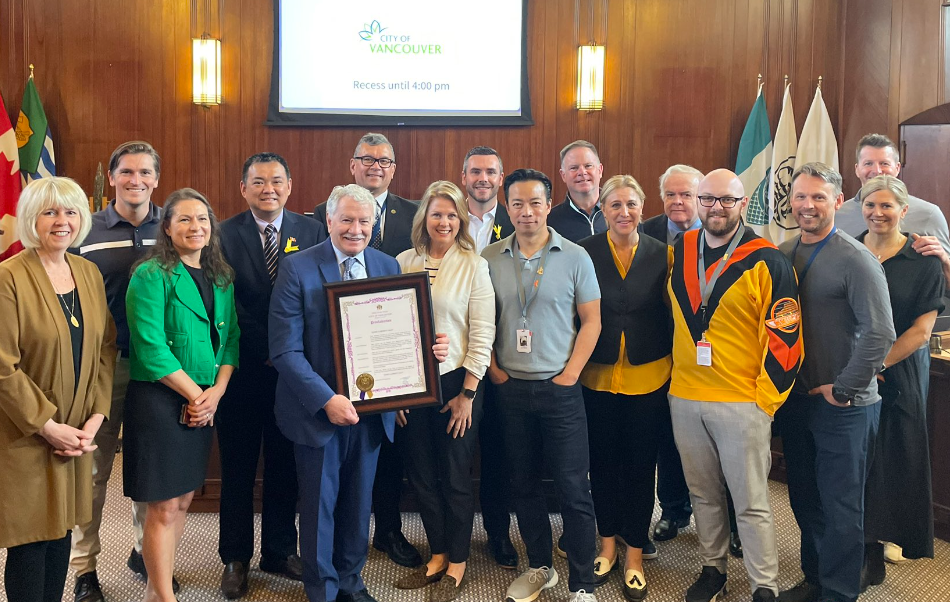 Former Vancouver Canucks colour commentator John Garrett stands with city councillors who have honoured him by proclaiming May 10 John Garrett Day