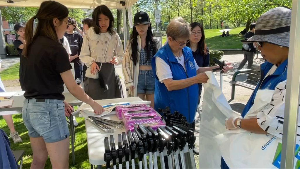 people stand in front of a table grabbing garbage bags and tools to help clean up chinatown