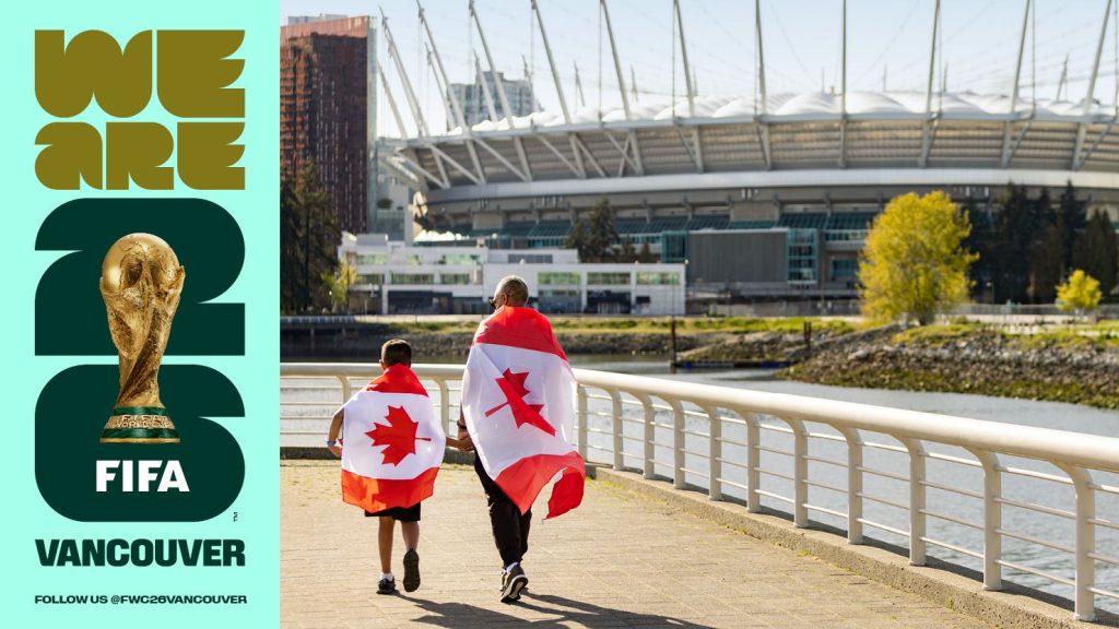 Two people wearing Canadian flags walk in the direction of BC Place on a sunny day.