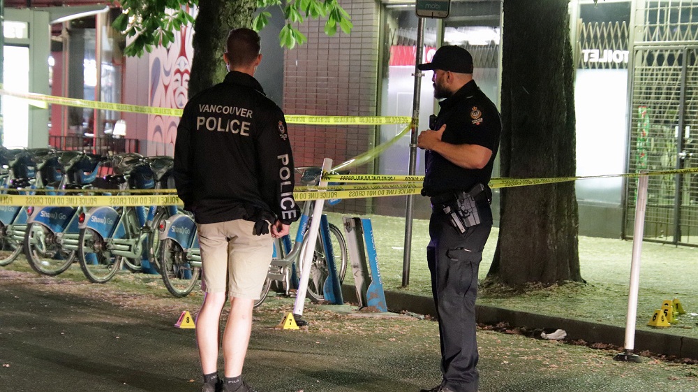 Two police officers talking at a crime scene near Davie Street and Bute Street in Vancouver
