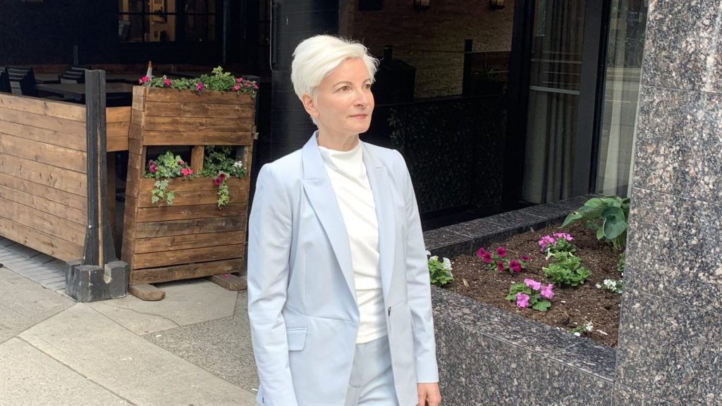 a woman standing in a powder blue suit outside. Atira has names catherine roome its new ceo
