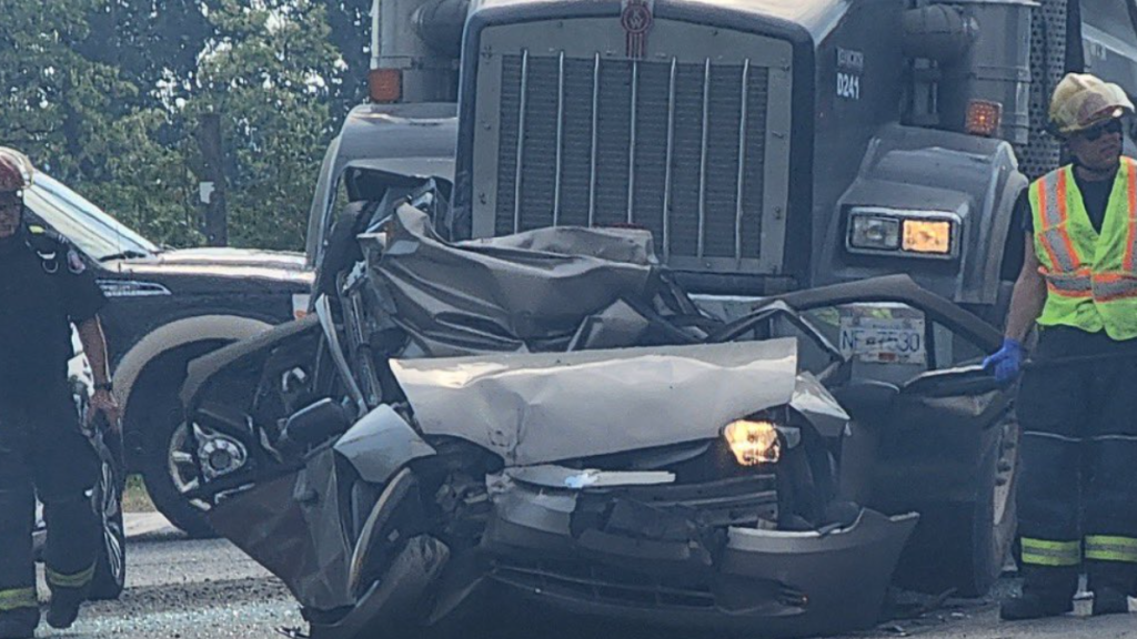 A dump truck is crushing a car.