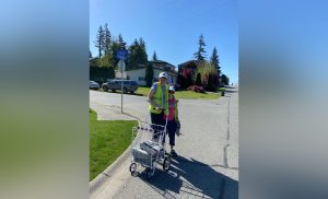 Amy Dirks two people stand outside on the sidewalk while one holds a newspaper carrier. the mother of amy dirks is speaking out about how the fraser valley transit stirke is impacting their family