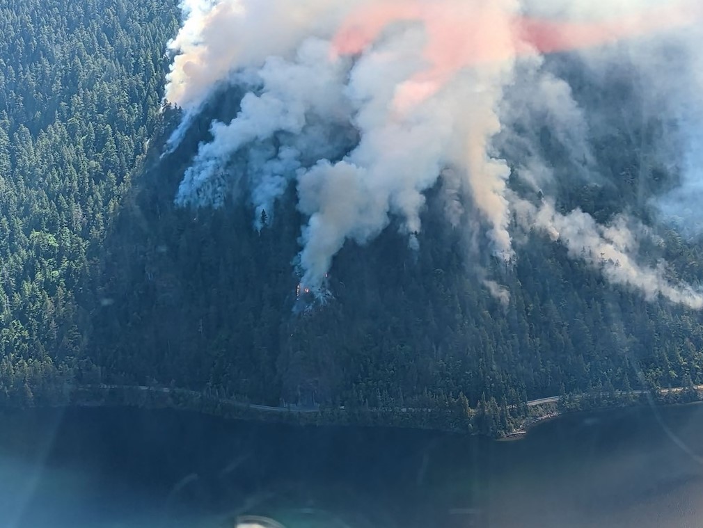 flames and smoke billowing due to the cameron bluffs wildfire on vancouver island