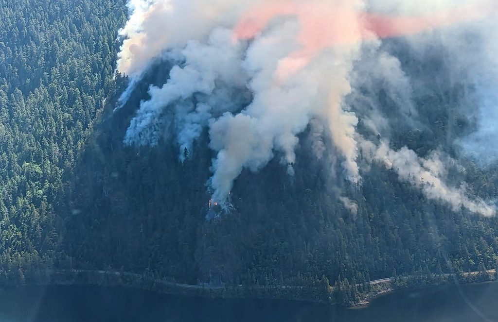 The Cameron Bluffs fire is seen burning from overhead. Smoke is seen blowing above the fire.