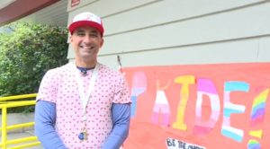 a man stands in front of a sign that reads pride that was created in front of a north vancouver school