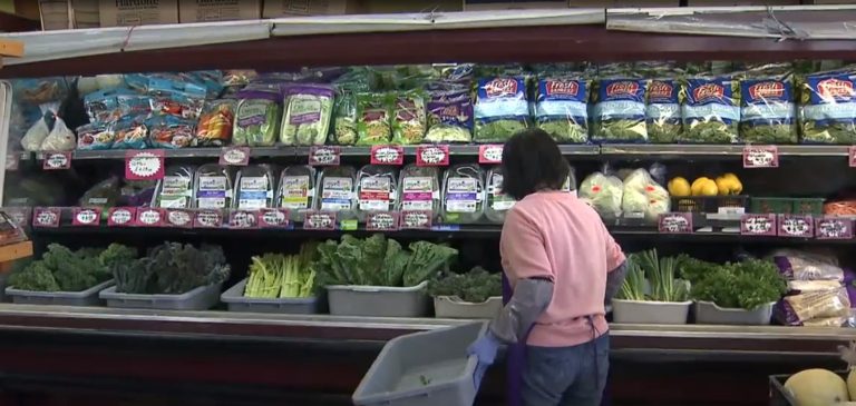 inside of a grocery store a woman stocks produce on the shelves. the east west market in vancouver was broken into on wedneasdy by a man who stole food