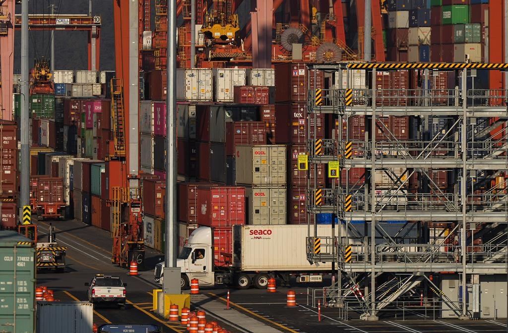 dozens of cargo containers seen on a ship with a semi truck driving underneath