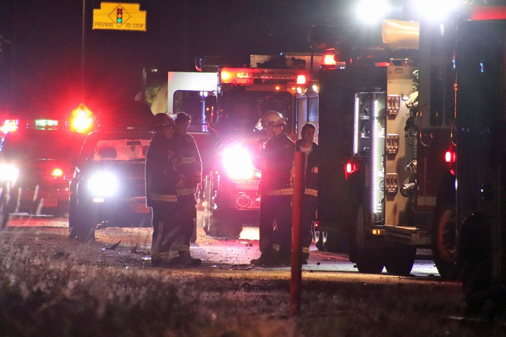 paramedics stand in front of emergency vehicles at the scene of a crash in surrey on sunday morning