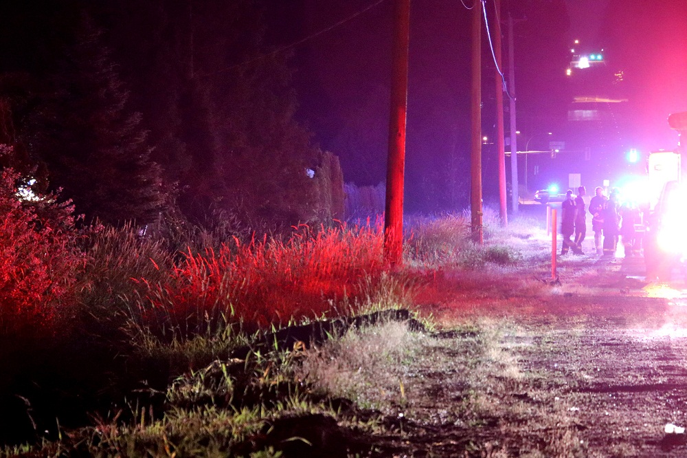 the scene of a crash that left three people hurt. a wooded area is seen and emergency personelle in the distance.