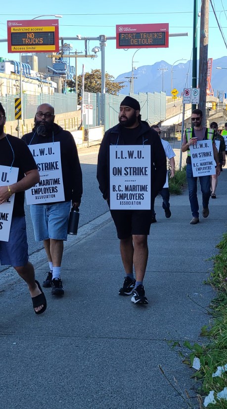 thousands of port workers are on strike. workers walk outside picketing with signs