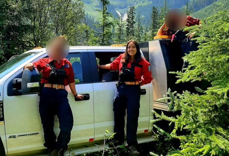BC Wildfire Service firefighter Devyn Gale is pictured near a pickup truck alongside two other service members, whose faces are blurred