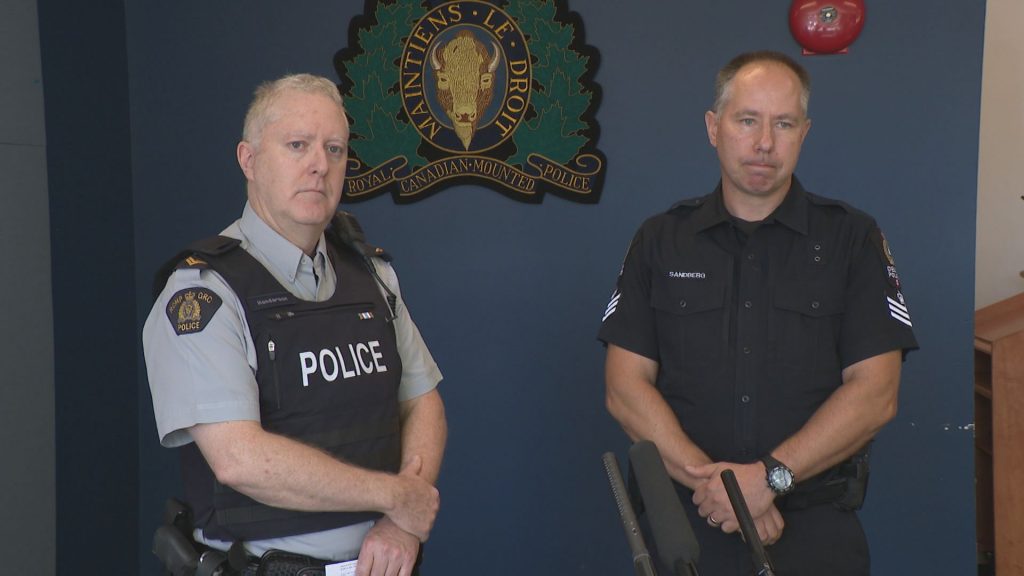 RCMP Cpl. Ian Henderson stands with another officer at a press conference