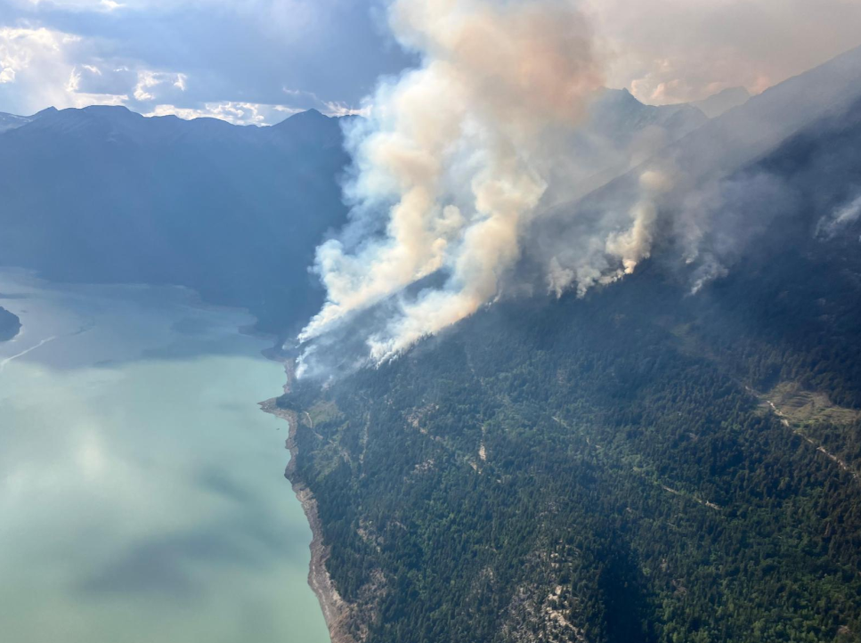 The Downton Lake Fire burns between hills on the right and the lake itself on the left.