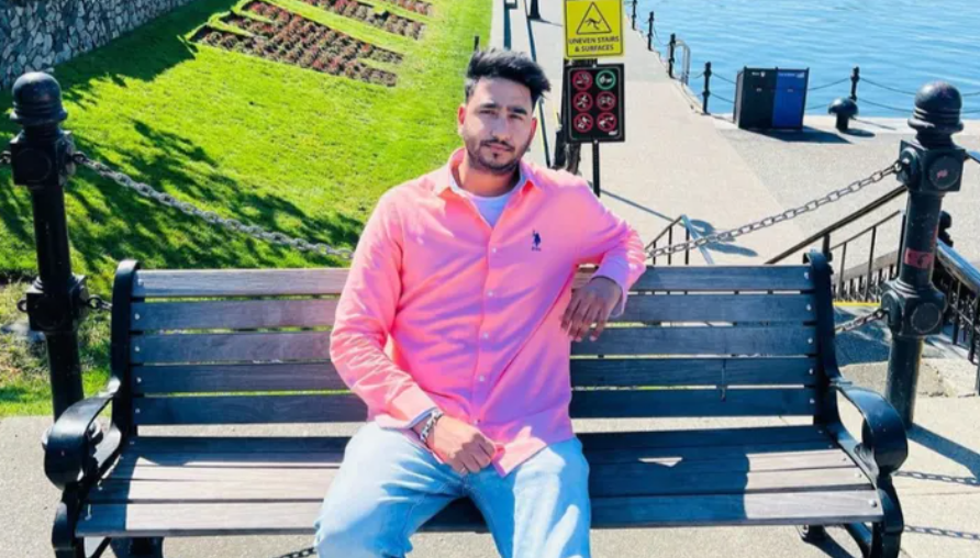 a man sits on a bench outside wearing a pink shirt and blue jeans. He has a short beard and dark black hair. The family has identified dilpreet singh as the victim of a fatal crash that happened in vancouver
