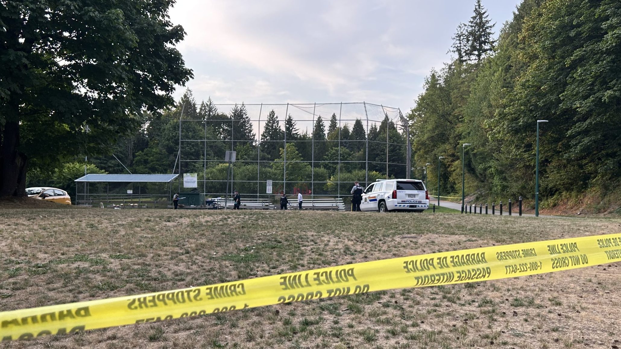 Yellow police tape blocks a field, and a park that contains a baseball diamond