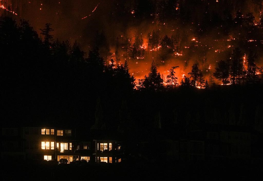 The McDougall Creek wildfire burns on the mountainside above a home in West Kelowna, B.C., on Friday, August 18, 2023.