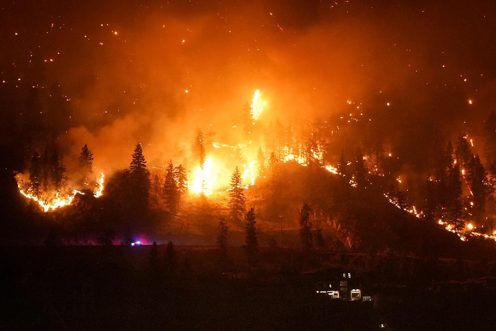 The McDougall Creek wildfire burning on the mountainside above a lakefront home, in West Kelowna, B.C., on Friday, Aug. 18, 2023