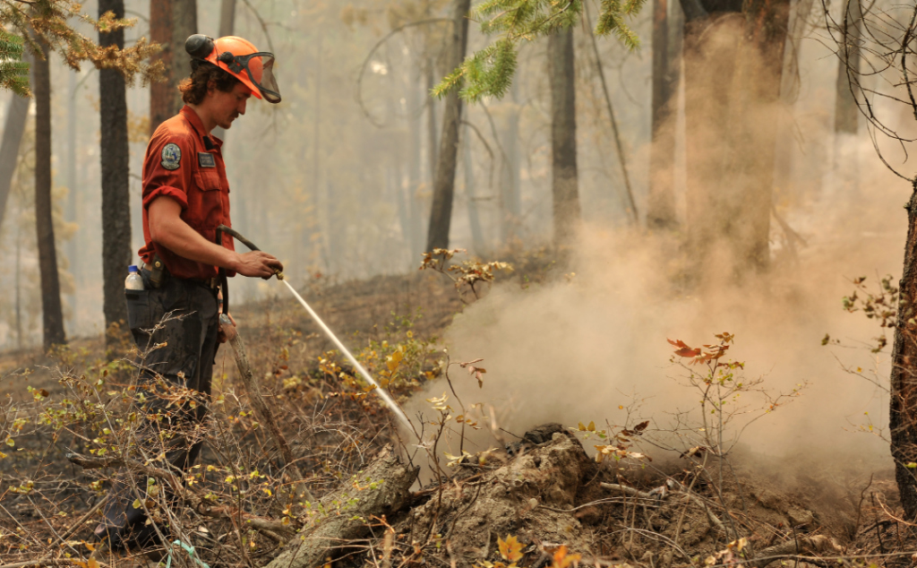 A BC Wildfire Service firefighter douses hot spots and flames from the McDougall Creek wildfire in West Kelowna