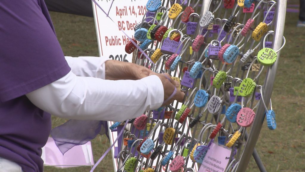 A person is seen putting a lock on a heart shaped object that is filled with locks