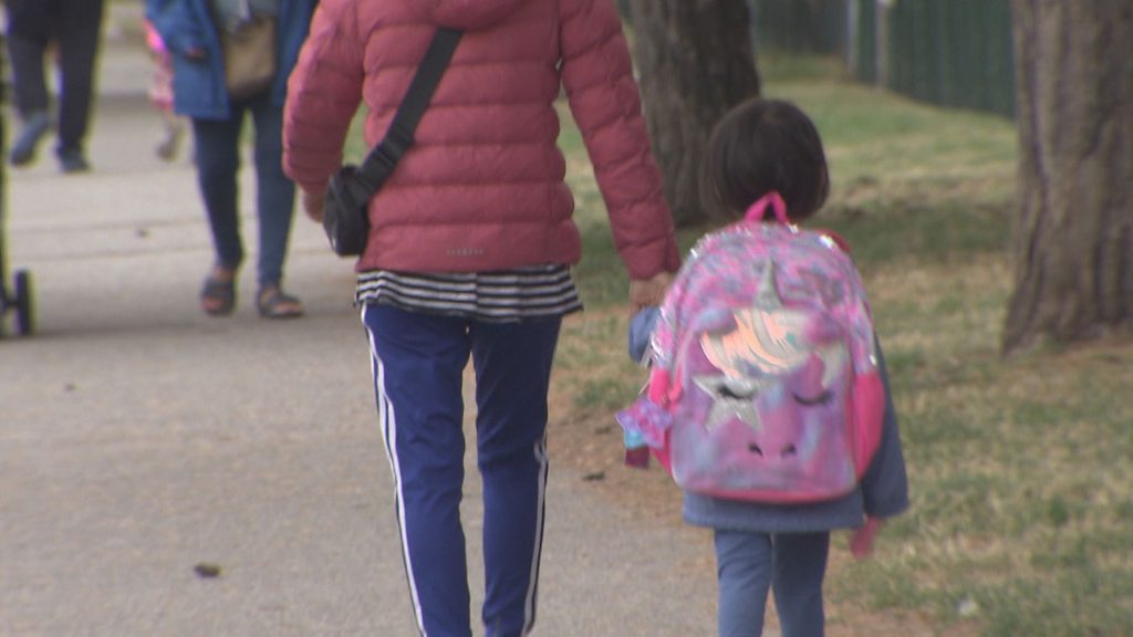 A caregiver and child walk down a street