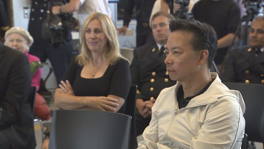 Vancouver Mayor Ken Sim is seen sitting in a crowd of people