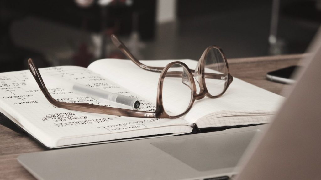 A stock image of eyeglasses on an open book.