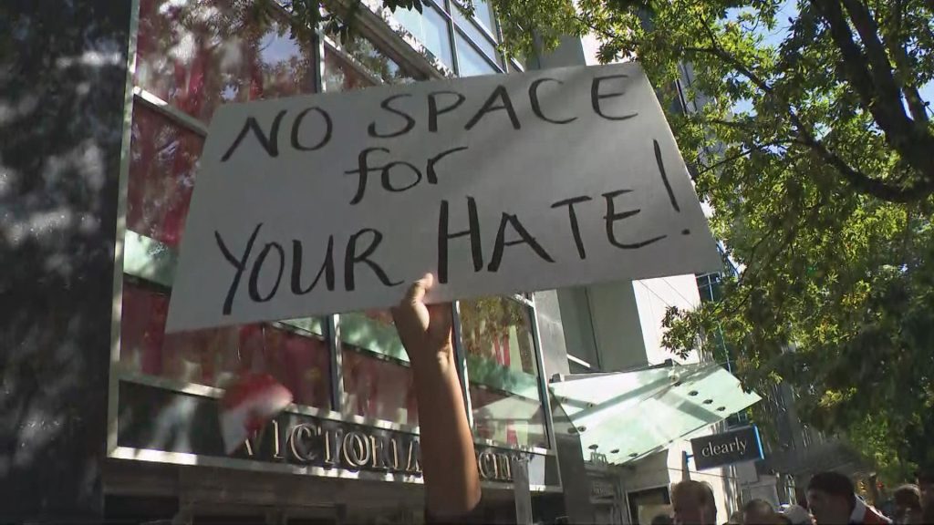 People hold signs up at protests and counter protests in Vancouver