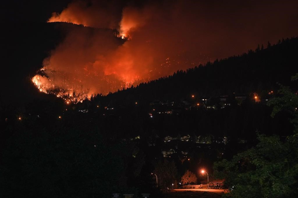 The McDougall Creek wildfire burns on the mountainside above houses in West Kelowna, B.C., on Friday, August 18, 2023.