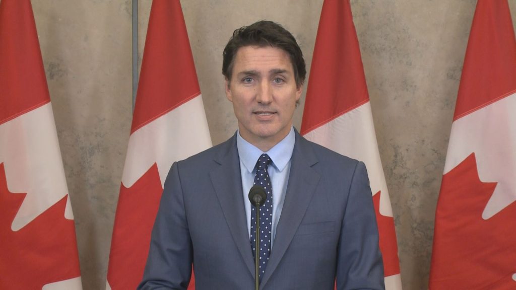 Photo of Justin Trudeau speaking in front of Canadian flags.