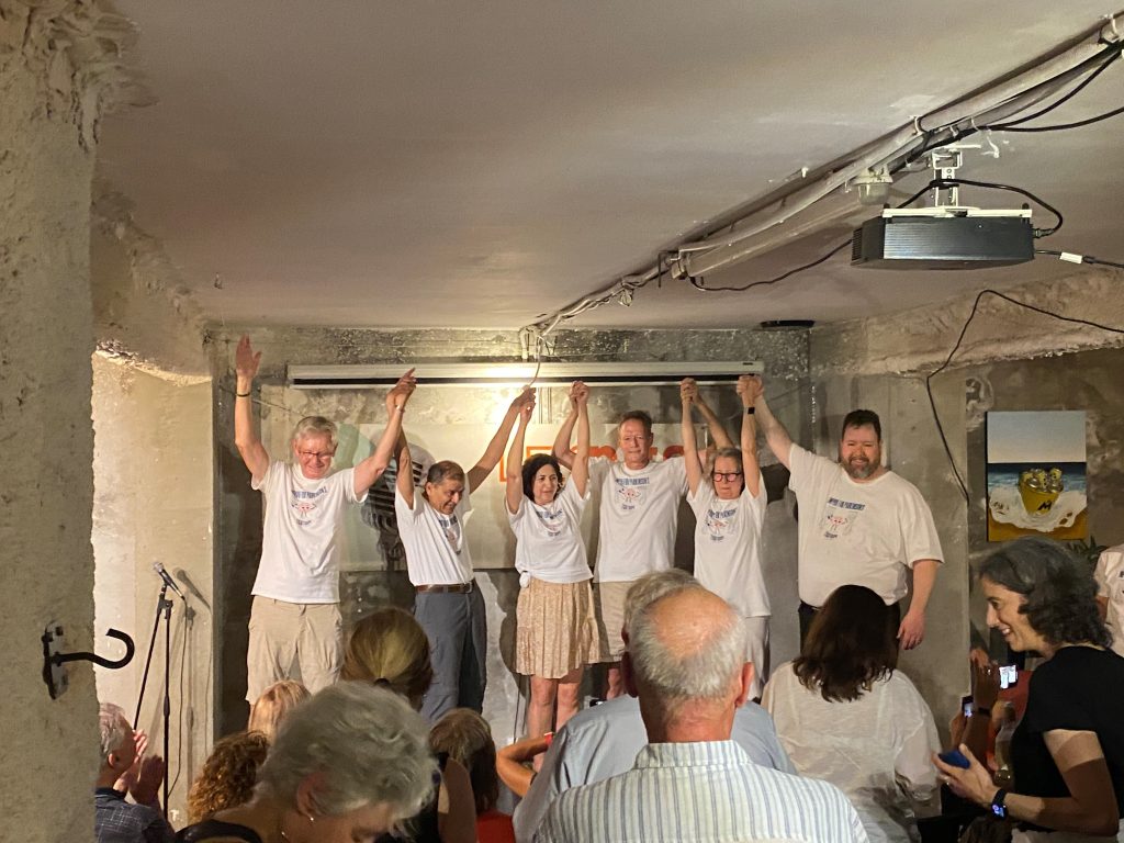 The Parkinson's Disease Performance Troupe holds hands and raises them in the air after a performance