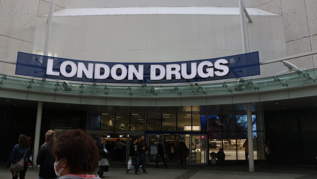 People walk in and out of the London Drugs store on the corner of Granville and Georgia Street.